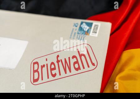 Augusta, Baviera, Germania - 29 settembre 2023: Busta con iscrizione posta votazione sul FOTOMONTAGGIO della bandiera nazionale tedesca *** Umschlag mit Aufschrift Briefwahl auf Deutschland Landesflagge FOTOMONTAGE Foto Stock