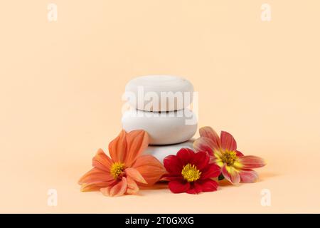 Piedistallo rotondo in legno con podio, presentazione di prodotti cosmetici di bellezza, mockup vuoto su sfondo pastello arancio con dahlia di fiori Foto Stock