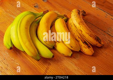 banane dal verde al sovramaterasso su fondo di legno Foto Stock
