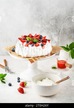 Torta Anna Pavlova fatta in casa con fragole fresche, mirtilli, lamponi, crema alla vaniglia e salsa di fragole. Ricetta estiva per dessert alla meringa, menu Foto Stock