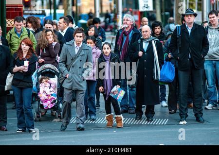 Pendolari diretti a casa all'attraversamento pedonale fuori dalla stazione di Flinders Street a Melbourne, Australia Foto Stock