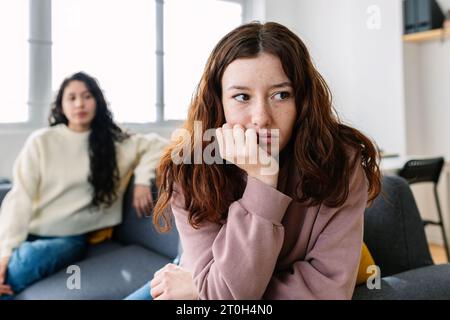 Due amici arrabbiati seduti separatamente sul divano Foto Stock