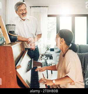 Coppia anziana che suona il pianoforte per la musica in salotto per legare, divertirsi o divertirsi. Felice, sorriso e anziano uomo e donna asiatico dentro Foto Stock