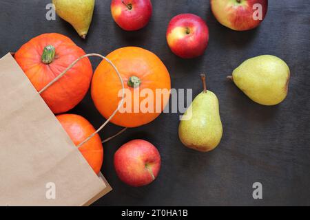 Borsa Kraft e frutta e verdura sul tavolo. Il Ringraziamento e il design autunnale. Sfondo autunnale con zucche mature, mele e pere su A. Foto Stock