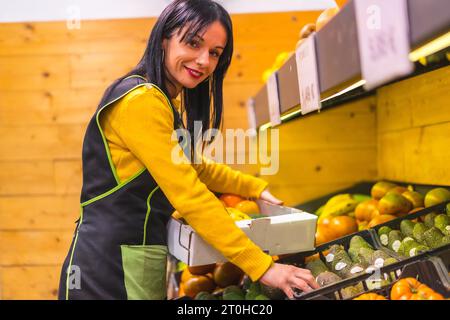 Bruna che lavora per ordinare frutta in un locale di fruttivendolo Foto Stock