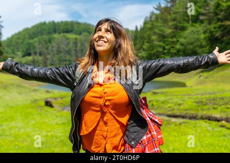 Stile di vita di una giovane donna che si gode l'estate nel bacino idrico di Domiko, un lago con pini intorno e splendidi fiori. Un lago in Navarra Foto Stock