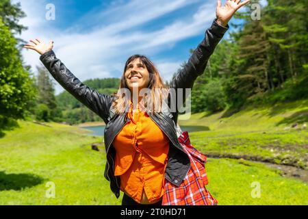 Stile di vita di una giovane donna che si gode l'estate nel bacino idrico di Domiko, un lago con pini intorno e splendidi fiori. Un lago in Navarra Foto Stock