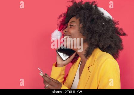 Giovane donna africana che ha una piacevole conversazione al telefono con indosso una giacca gialla Foto Stock