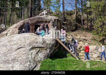 PUTNA, ROMANIA - 30 APRILE 2023: Numerosi pellegrini e turisti visitano la roccia con la grotta di Daniele l'Eremita. Foto Stock