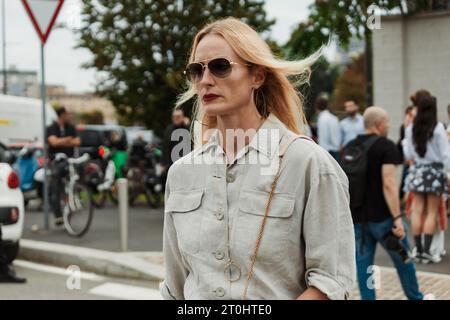 Un ospite indossa occhiali da sole, camicia grigia e gonna, visti all'esterno della sfilata PRADA durante la settimana della moda milanese, abbigliamento donna primavera/estate 2024. Foto Stock