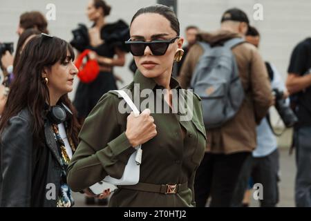 Evangelie Smyrniotaki indossa occhiali da sole neri, orecchini dorati, abito abbottonato verde visto all'esterno della sfilata PRADA durante la settimana della moda milanese Spri Foto Stock