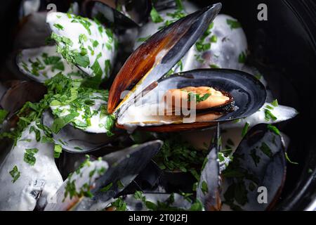 Cozze bollite in salsa cremosa in una padella nera Foto Stock