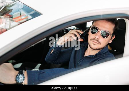 Un giovane che parla al telefono all'interno della sua auto Foto Stock