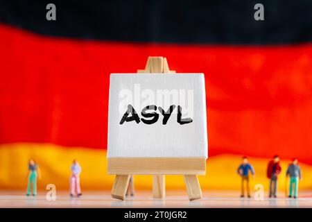 Augusta, Baviera, Germania. 7 ottobre 2023. Bandiera della Germania con persone in miniatura e una tela con iscrizione: Asilo FOTOMONTAGGIO *** Deutschlandflagge mit Miniatur Menschen und einer Leinwand mit Aufschrift: Asyl FOTOMONTAGE Credit: Imago/Alamy Live News Foto Stock