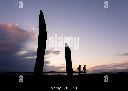 Stenness, Orcadi, Regno Unito. 7 ottobre 2023. Due turisti visitano le magnifiche pietre permanenti di Stenness al tramonto, nelle Orcadi, Regno Unito. Le enormi pietre di Stenness sono tutto ciò che rimane di un grande cerchio di pietre su un antico sito cerimoniale che risale a 5000 anni fa. Crediti: Peter Lopeman/Alamy Live News Foto Stock