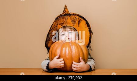 Preparazione per le vacanze di Halloween. Trick o dolcetto. Bambino con cappello da strega con jack-o-lantern di zucca di halloween. Simpatico ragazzo in costume di Halloween con Foto Stock