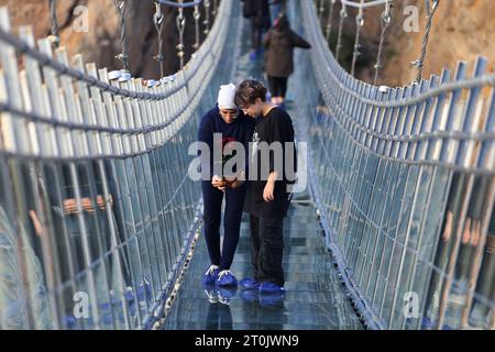 Hir, Ardabil, Iran. 5 ottobre 2023. Un'adolescente iraniana scatta una foto dal ponte sospeso in vetro ad arco nell'area ricreativa di Hir vicino alla città di Ardabil. Con i suoi 208 metri di lunghezza, 1,5 metri di larghezza e 100 metri di altezza, il ponte è un luogo frequentato dai turisti. (Immagine di credito: © Rouzbeh Fouladi/ZUMA Press Wire) SOLO USO EDITORIALE! Non per USO commerciale! Foto Stock