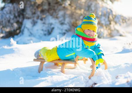 Piccolo bambino su slitta. Giro in slitta invernale. Slitta per bambini. Bambino piccolo in slitta. I bambini giocano all'aperto sulla neve. Foto Stock