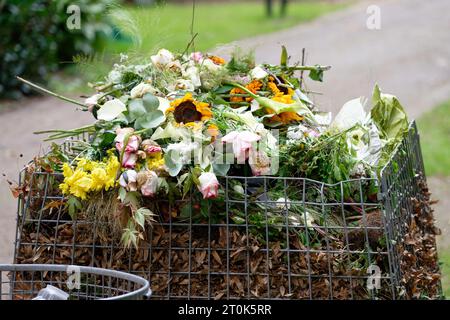 contenitore della spazzatura in un cimitero con molti fiori selvaggi Foto Stock