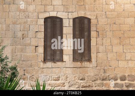 Sfondo con finestre a persiane sul muro dell'antica casa israeliana Foto Stock