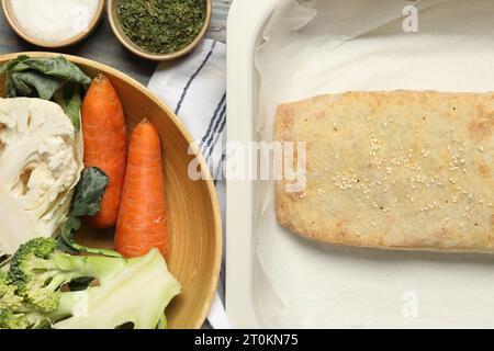 Delizioso strudel con verdure su tavolo di legno grigio, piatto Foto Stock