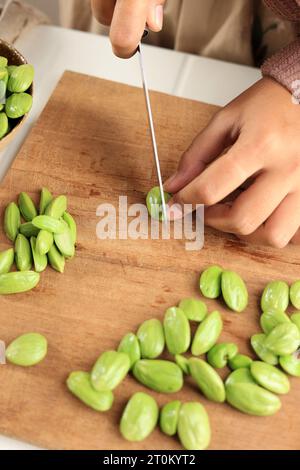 Chef donna che affetta Pete Cut o Parkia Speciosa su legno Foto Stock