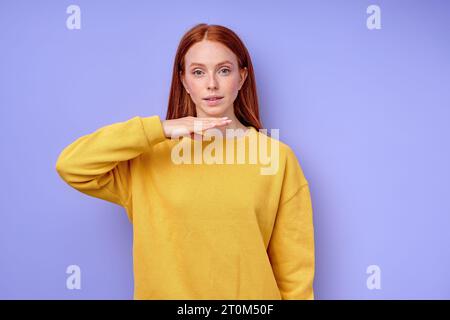 attraente ginger girl che utilizza i gesti per comunicare parlare parlare parlare parlare con gli amici, ritratti ravvicinati foto studio con sfondo blu isolato Foto Stock