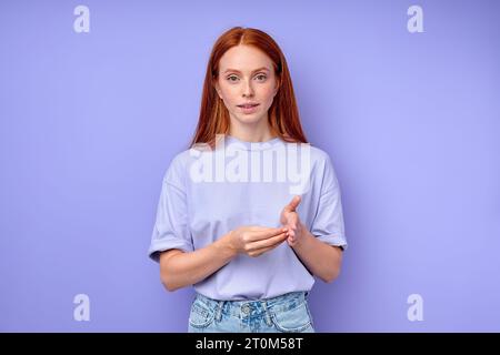 Primo piano sorridente ragazza sorridente dai capelli rossi che usa il linguaggio dei segni per comunicare. Donna Millennial felice con disabilità uditiva che mostra gesti Foto Stock