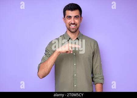 Allegro uomo barbuto bruna che mostra la lettera H. simbolo del linguaggio dei segni per essere umano sordo su sfondo blu. isolato Foto Stock