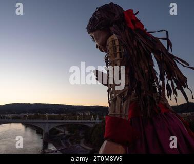 Chattanooga, Tennessee, USA. 7 ottobre 2023. Little Amal, una marionetta torreggiante di una bambina siriana rifugiata di 10 anni, si affaccia sul fiume Tennessee mentre cammina attraverso lo storico ponte pedonale di Walnut Street. Amal sta viaggiando attraverso gli Stati Uniti per sensibilizzare le persone sulle questioni affrontate dai rifugiati e dagli immigrati, celebrando le arti e la comunità. (Immagine di credito: © sue Dorfman/ZUMA Press Wire) SOLO USO EDITORIALE! Non per USO commerciale! Foto Stock