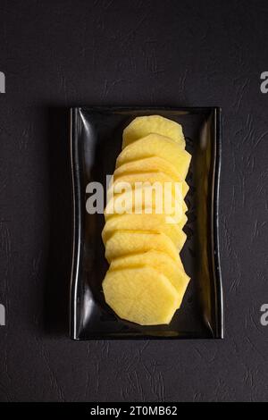 fette di patate su un piatto nero. Vista dall'alto. Cucina cinese, ingrediente per l'hot pot Foto Stock