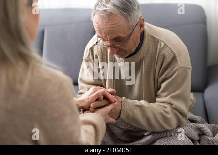 Testa ha sparato vecchio pensionato maschio coinvolto nella procedura di riabilitazione con giovane fisioterapista premuroso. uomo in pensione con sensazione di disabilità motoria Foto Stock