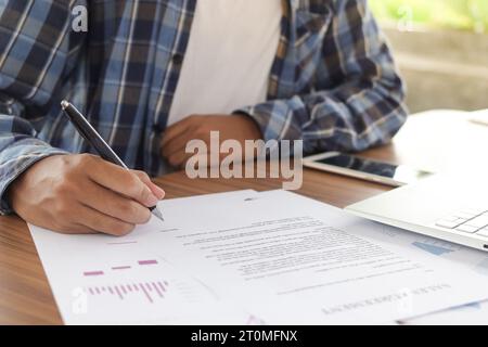 Primo piano del documento ufficiale di compilazione a mano di un uomo freelance, della firma del contratto e delle tasse. Documento dell'accordo commerciale e di vendita Foto Stock