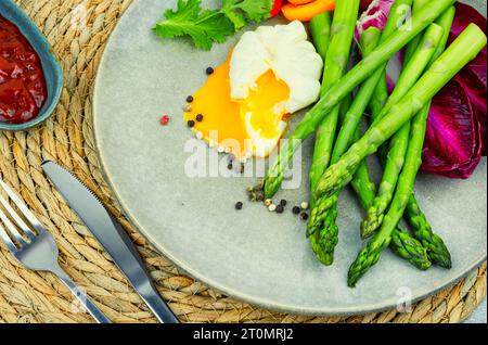 Insalata deliziosa con asparagi, lattuga, pomodoro e uova in camicia. Foto Stock