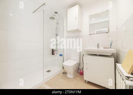 Bagno con comò in legno bianco e lavandino in porcellana bianca sotto uno specchio senza telaio Foto Stock