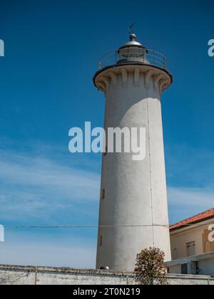 2023 25 luglio, Faro di Punta Tagliamento, Bibione, Italia. Popolare faro bianco con una torre in cemento e una luce attiva su una spiaggia tranquilla, costruito Foto Stock