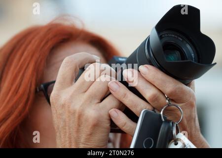 Donna rossa con zaino e abbigliamento mimetico che realizza fotografie di paesaggi in Alt de les Pedreres de Alcoi, Spagna Foto Stock