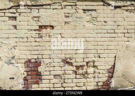 Un vecchio muro di mattoni dipinto di giallo con dolore usurato Foto Stock