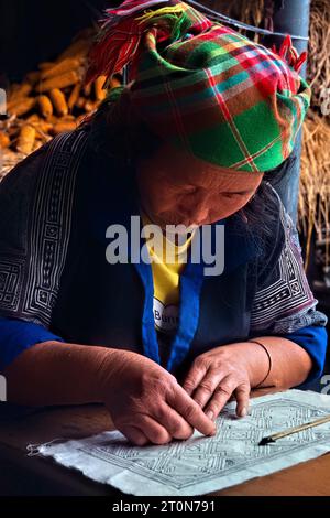 Una donna Flower Hmong disegna un modello per il suo ricamo tradizionale, Mu Cang Chai, Yen Bai, Vietnam Foto Stock