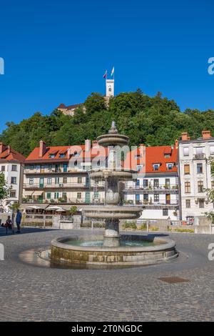 Lubiana, Slovenia - 13 luglio 2022: Fontana sulla piazza nuova (Novi Trg) e vista sulla città vecchia e sulla collina del castello nella capitale. Foto Stock