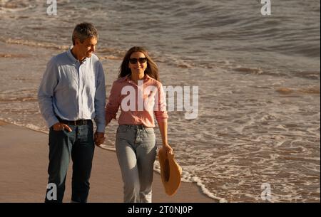 Romantica coppia di mezza età che fa una passeggiata lungo la spiaggia Foto Stock