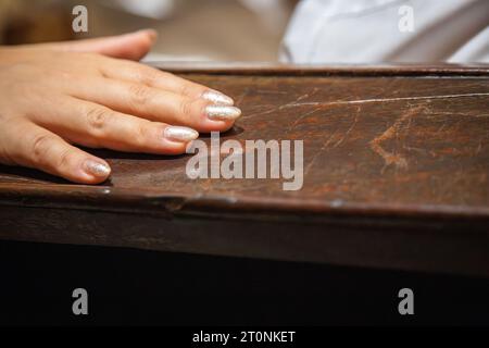 Dettaglio della mano di una donna appoggiata su una superficie di legno scura e invecchiata. Copia spazio Foto Stock