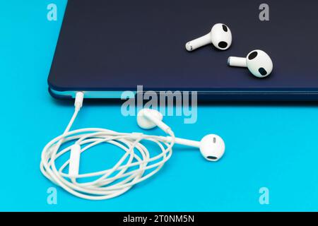 le cuffie wireless bianche si trovano su un computer portatile. collegamento delle cuffie al computer portatile. Le cuffie wireless offrono maggiore comfort rispetto a quelle cablate Foto Stock