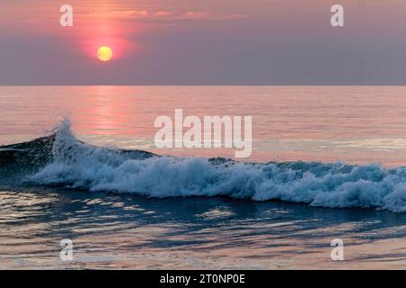 Il sole estivo sorge sull'Oceano Atlantico infondendo la costa con sfumature di rosa, viola e blu. - Salisbury, Massachusetts Foto Stock