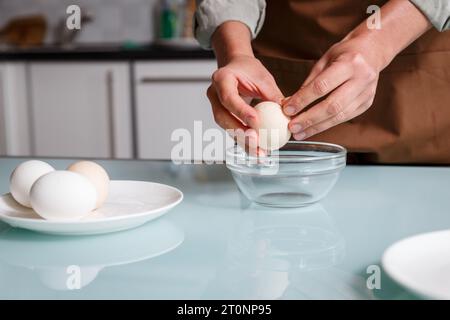 Mani femminili che si staccano dal guscio dell'uovo bollito su un tavolo di kithcen su un piatto di vetro. Preparazione delle uova bollite e concetto nutrizionale Foto Stock