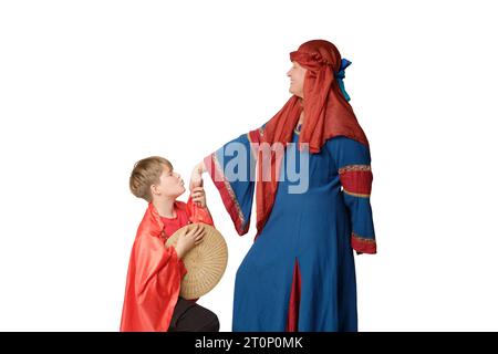 Una donna con un abito medievale europeo e un ragazzo che si piega al ginocchio le bacia la mano, isolata su sfondo bianco Foto Stock