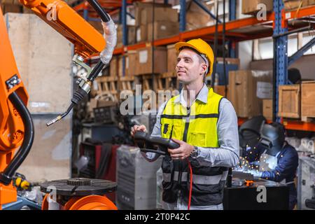 Uomo ingegnere moderno intelligente che utilizza la moderna tecnologia robotica. Configurazione del braccio di saldatura robotizzato nel processo di produzione dell'automazione in fabbrica Foto Stock