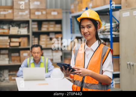 Ritratto giovane donna ingegnere felice lavoro personale inventario. Lavoratrice adolescente del sud-est asiatico in piedi nel magazzino di spedizione dei prodotti della fabbrica. Foto Stock