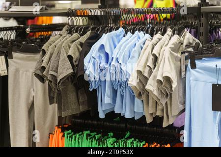 T-shirt da donna - camicie a manica corta appese su appendiabiti in un negozio di abbigliamento. Primo piano, sfondo. Affilatura selettiva. Foto Stock