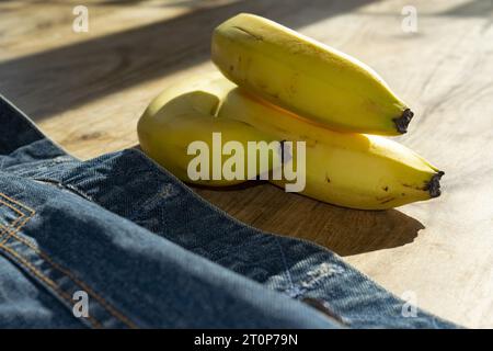 gruppo di banane vicino a una giacca di jeans Foto Stock